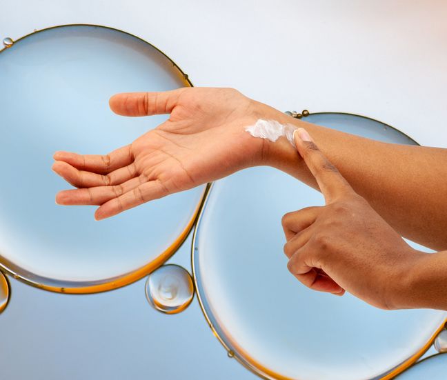 A hand putting on lotion on bubble background